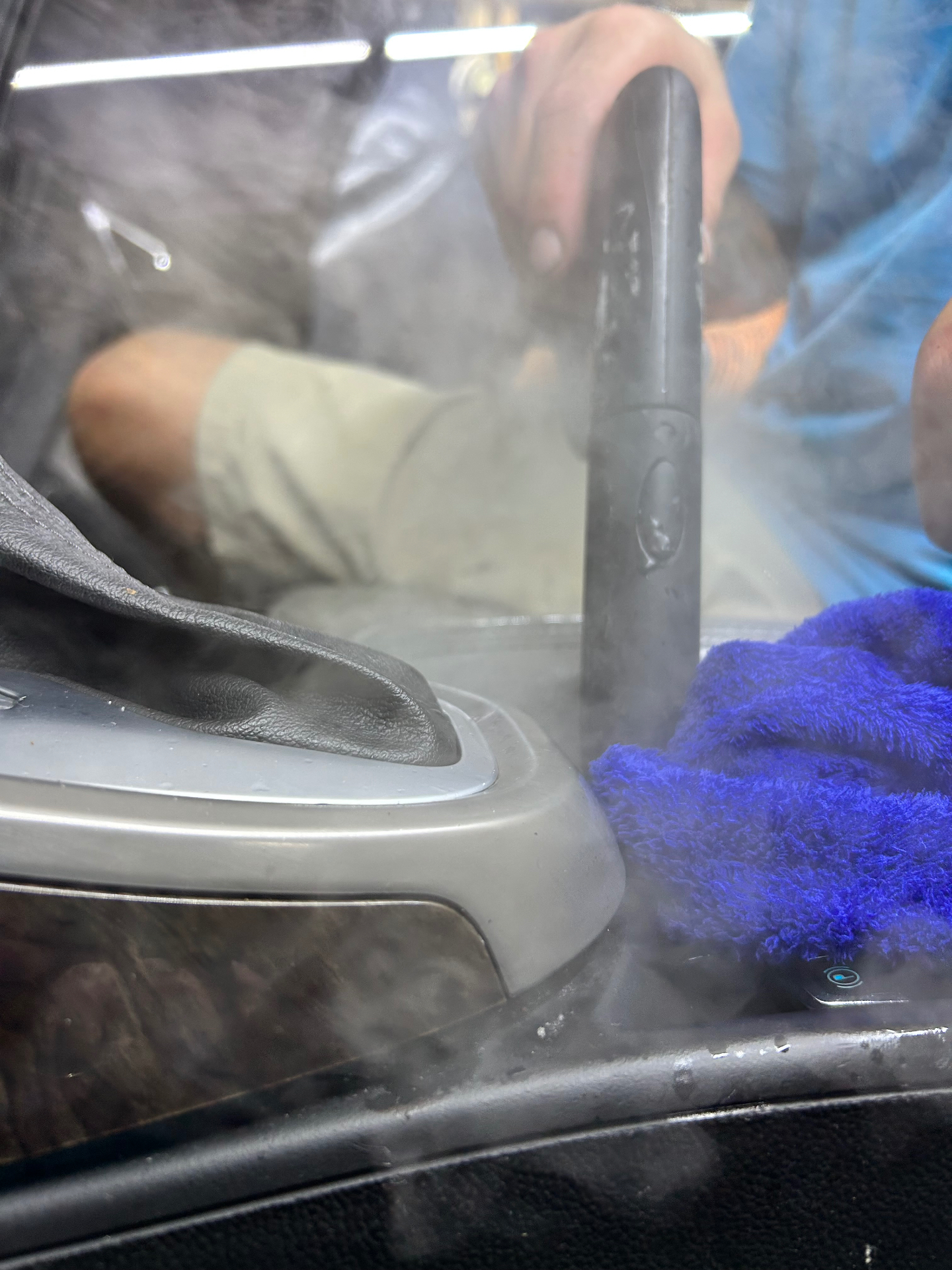 Steam cleaning a center console with a blue microfiber towel