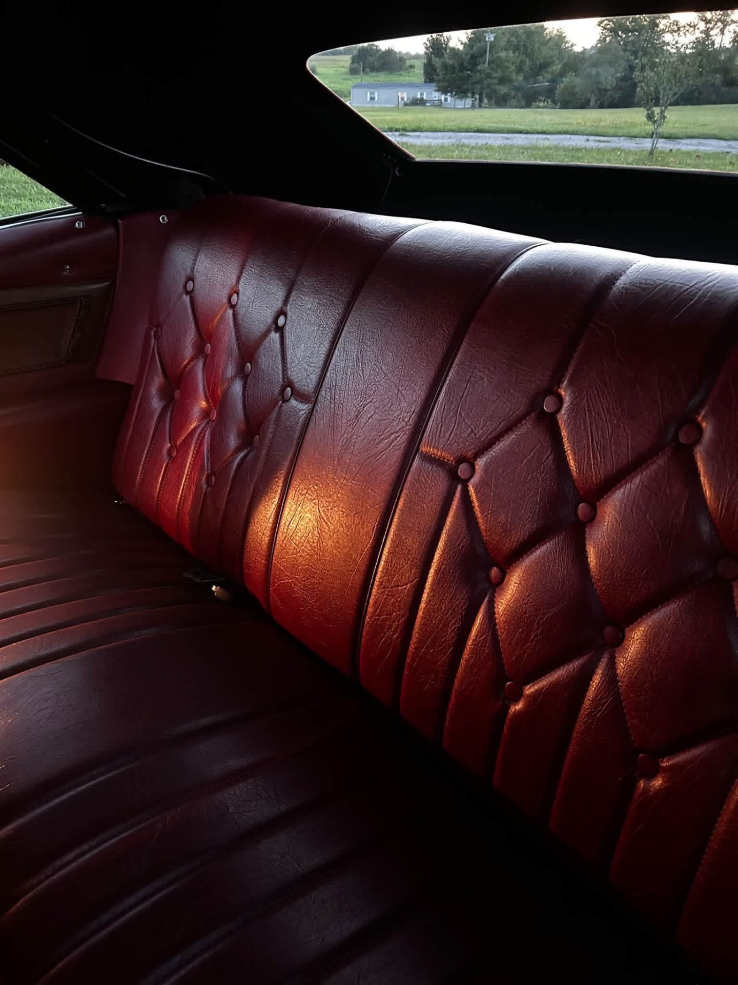 Maroon button-tufted leather backseat of a classic car after cleaning