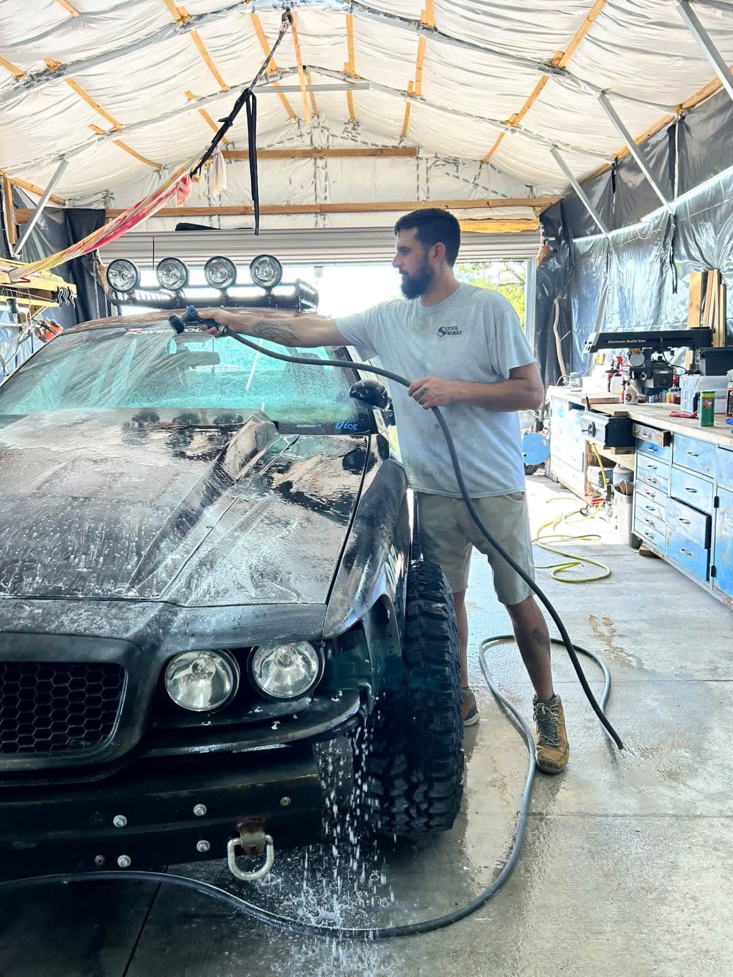 Detailer hand washing a car with foam in the shop bay