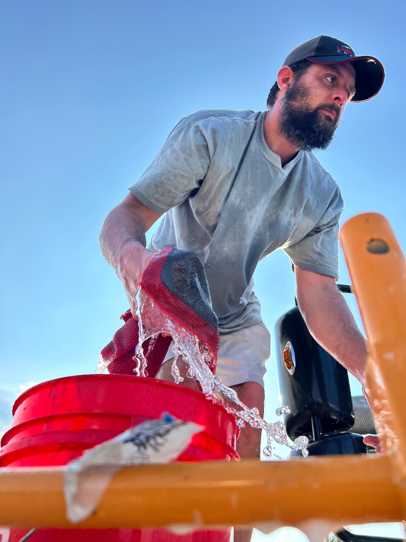Detailer wringing a wash mitt over a bucket during the wash stage
