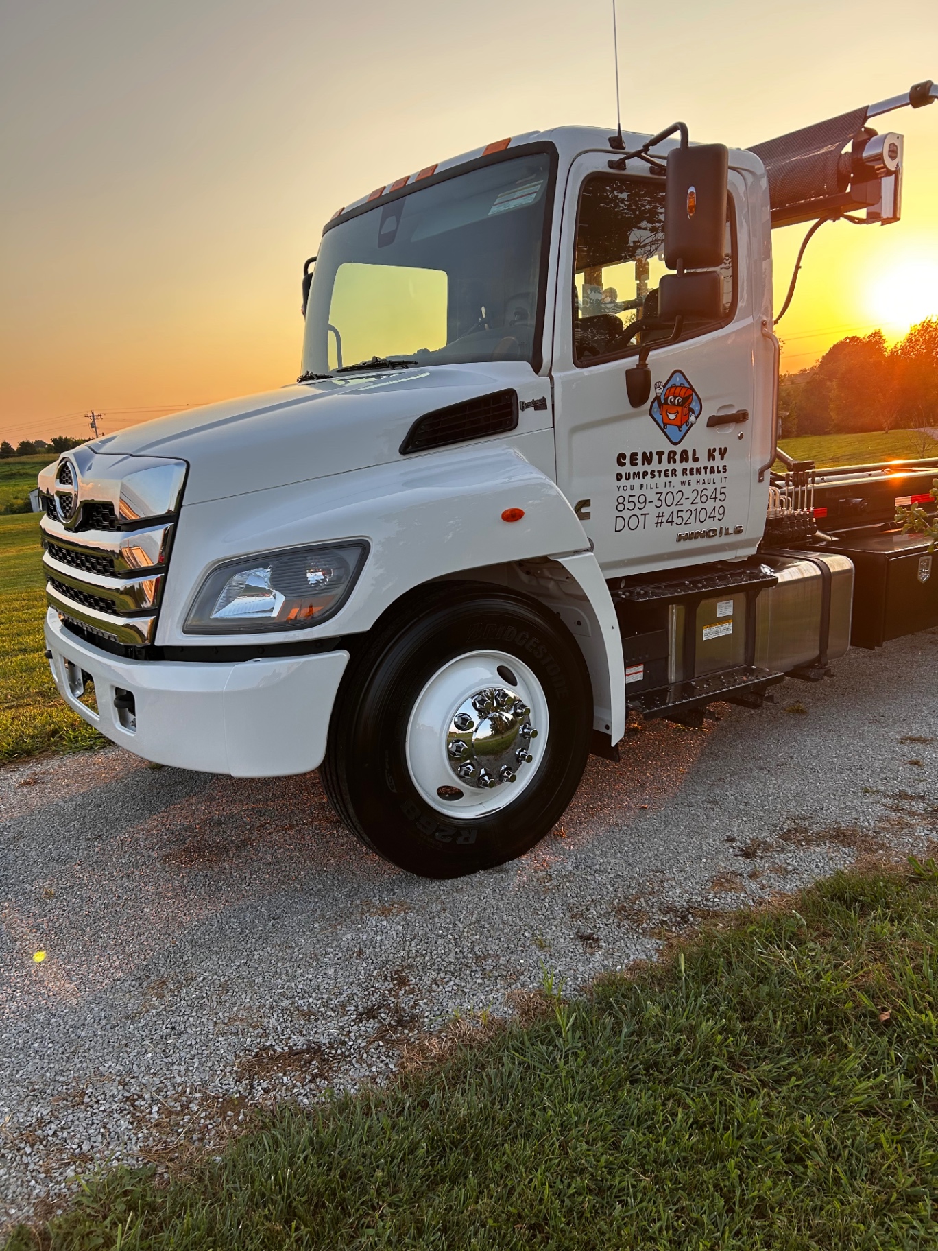 White Hino dumpster rental truck detailed and glowing at sunset