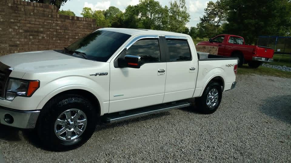 White Ford F-150 with polished wheels in a gravel lot