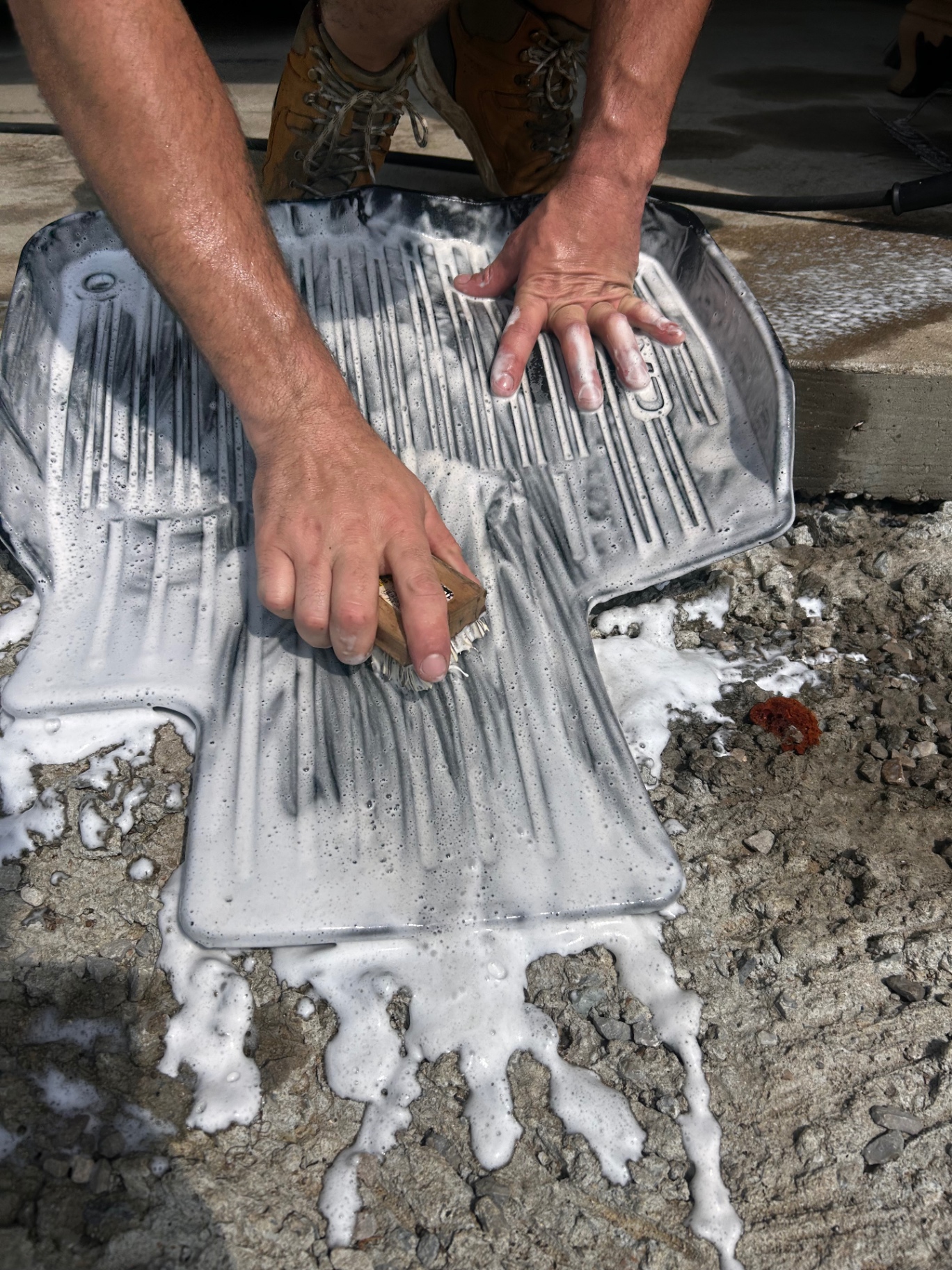 Hand scrubbing all-weather floor mats with foam and brush